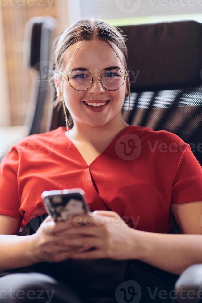 A businesswoman resting on a short break from work in a modern startup coworking center, using her smartphone to unwind and recharge. photo