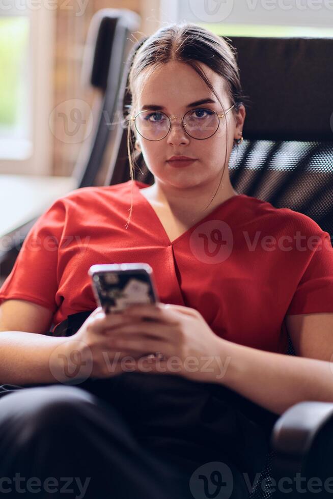 A businesswoman resting on a short break from work in a modern startup coworking center, using her smartphone to unwind and recharge. photo