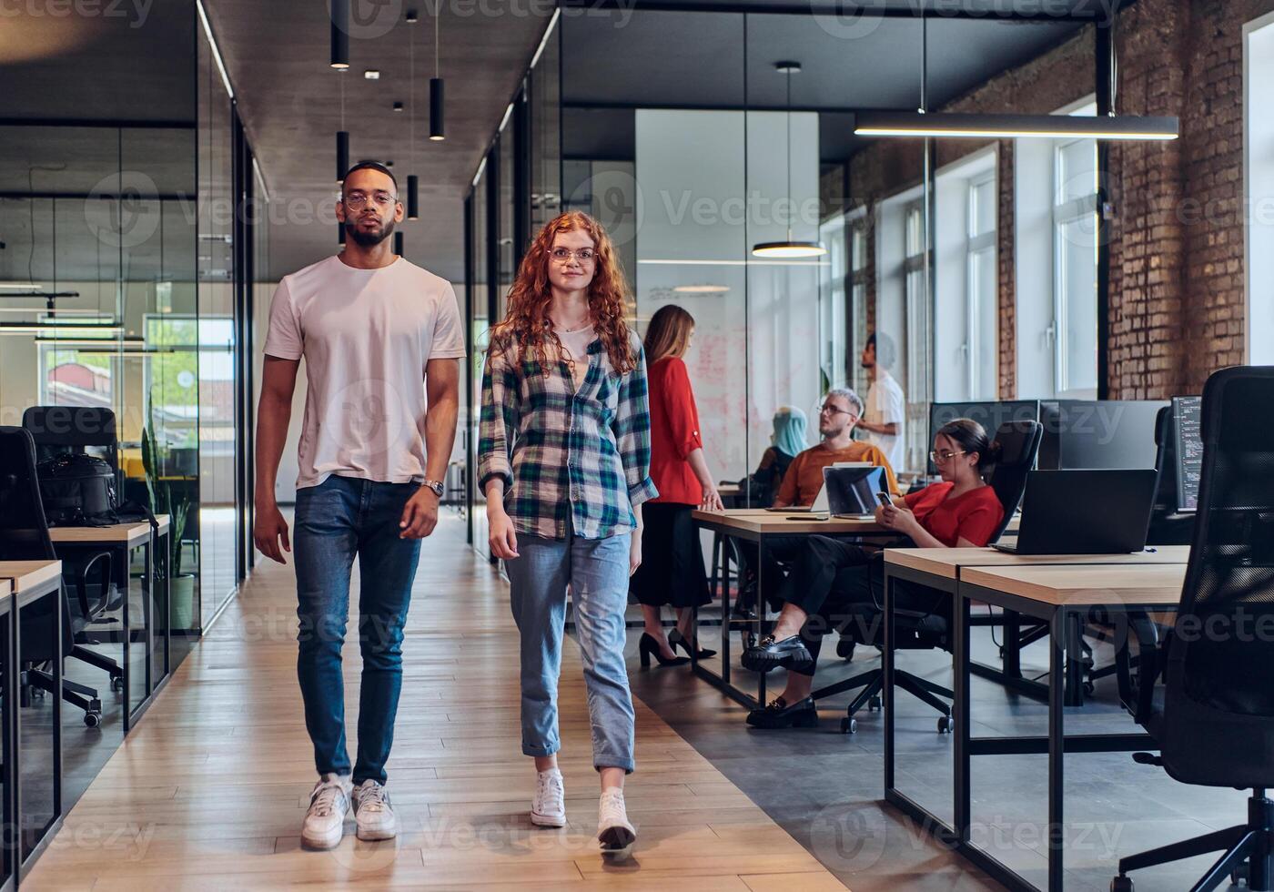 A young African American businessman and a modern businesswoman with orange hair stand side by side, arms crossed, exuding confidence and unity in a contemporary office setting, epitomizing dynamic photo