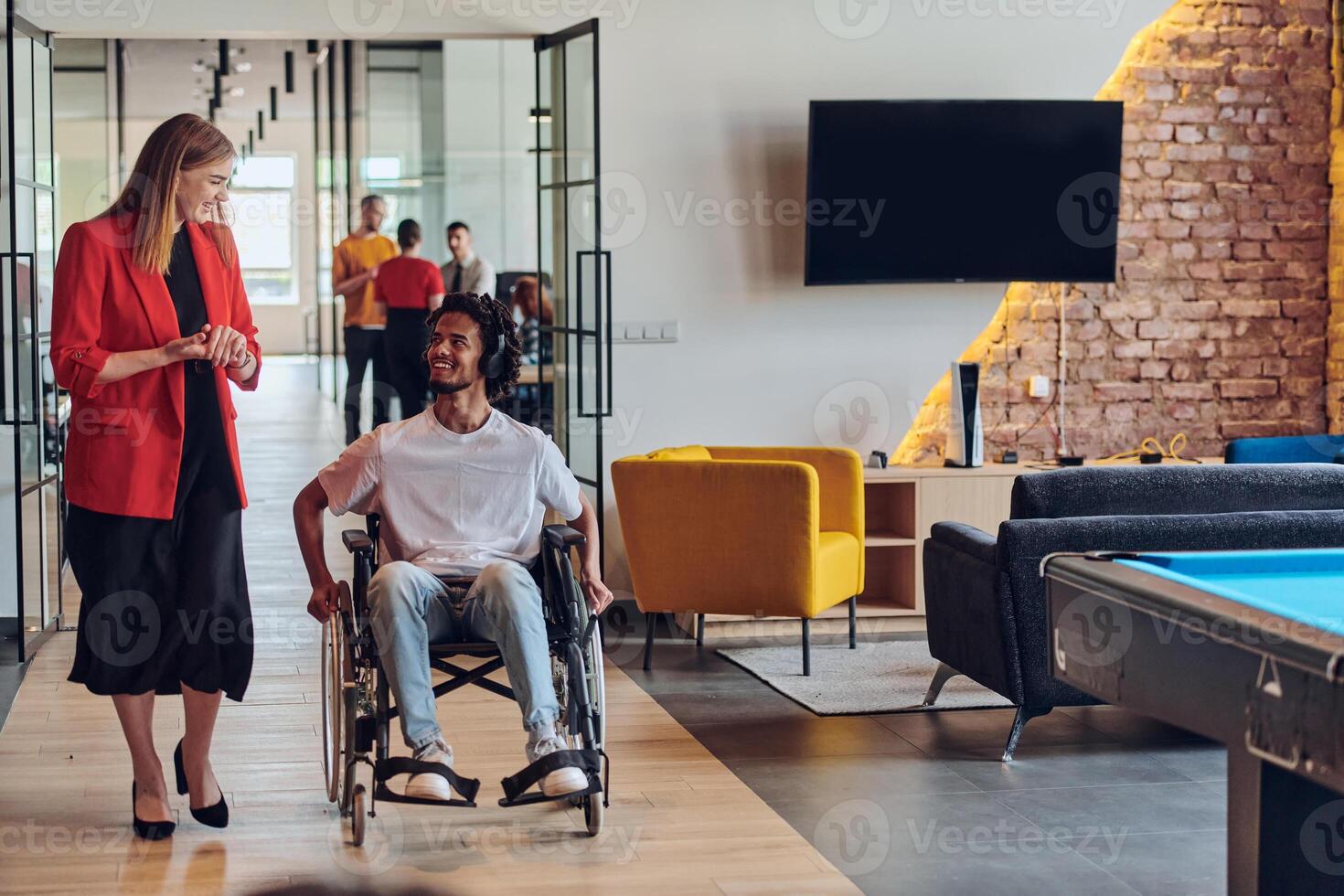 A group of young business people in a modern glass-walled office captures the essence of diversity and collaboration, while two colleagues, including an African American businessman in a wheelchair photo
