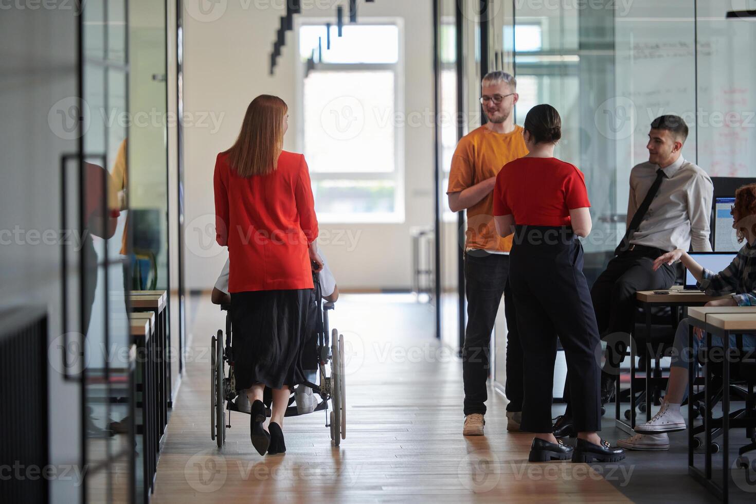 A group of young business people in a modern glass-walled office captures the essence of diversity and collaboration, while two colleagues, including an African American businessman in a wheelchair photo