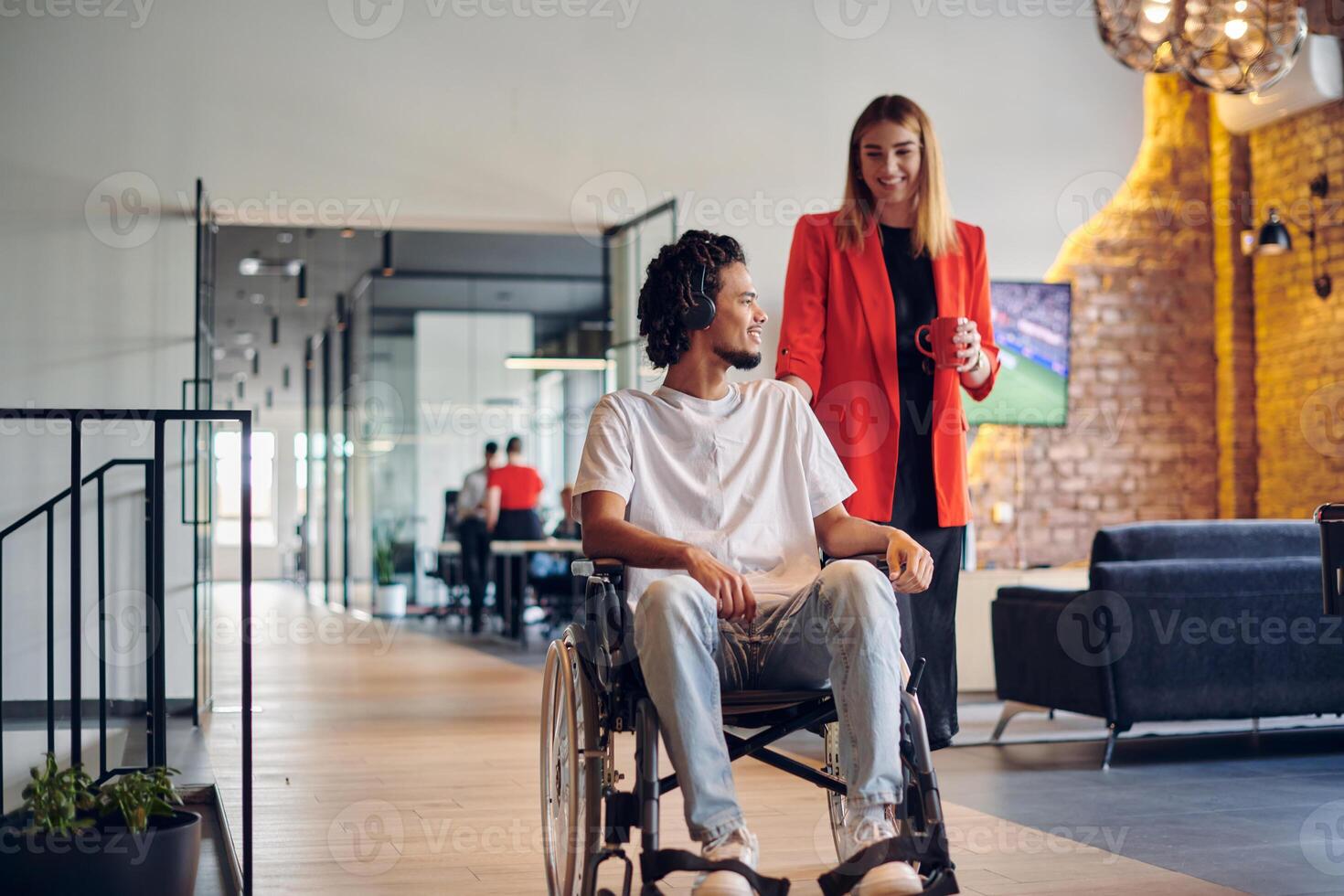 A group of young business people in a modern glass-walled office captures the essence of diversity and collaboration, while two colleagues, including an African American businessman in a wheelchair photo