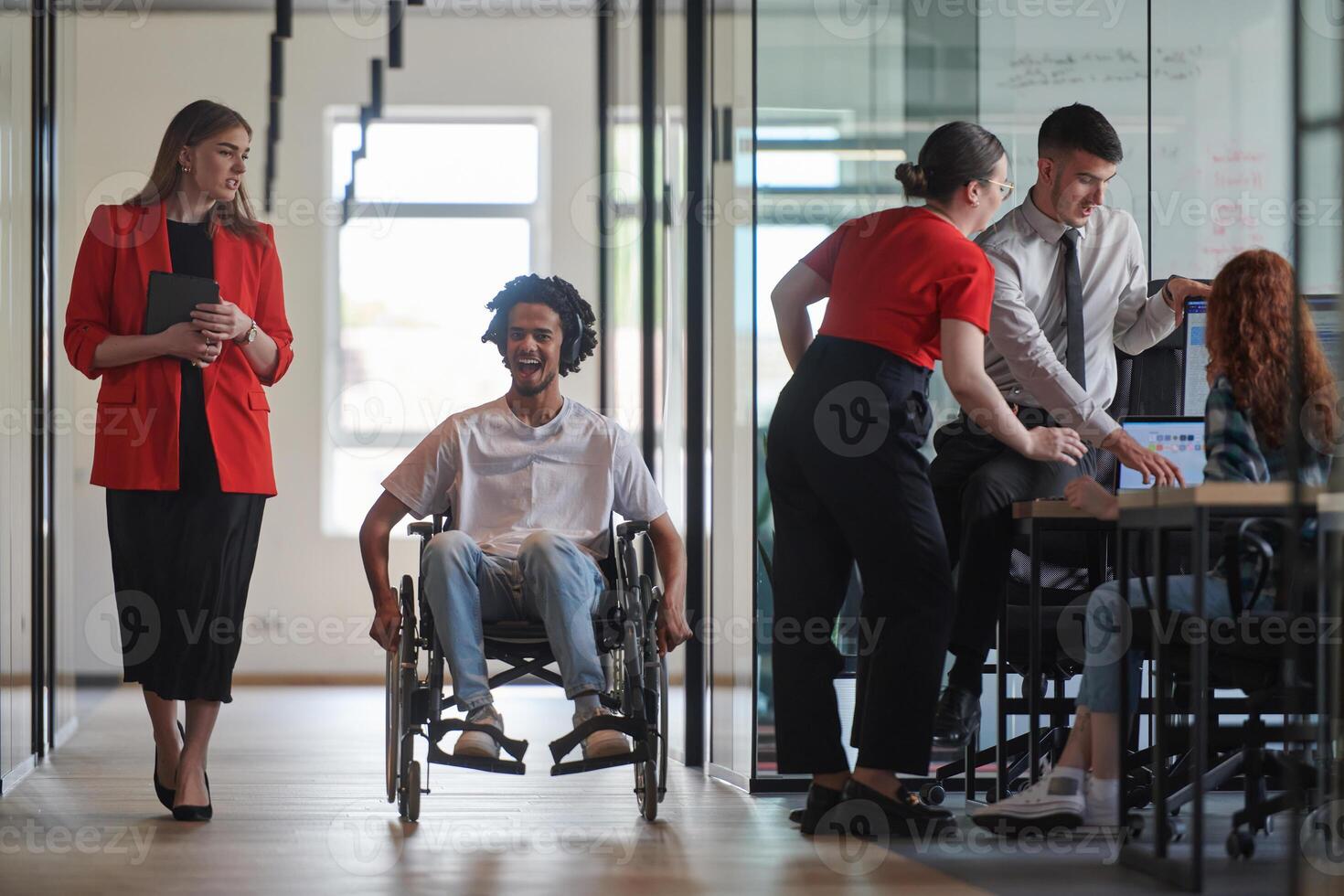 A group of young business people in a modern glass-walled office captures the essence of diversity and collaboration, while two colleagues, including an African American businessman in a wheelchair photo