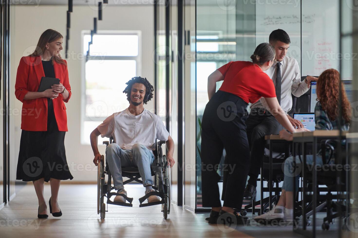 A group of young business people in a modern glass-walled office captures the essence of diversity and collaboration, while two colleagues, including an African American businessman in a wheelchair photo