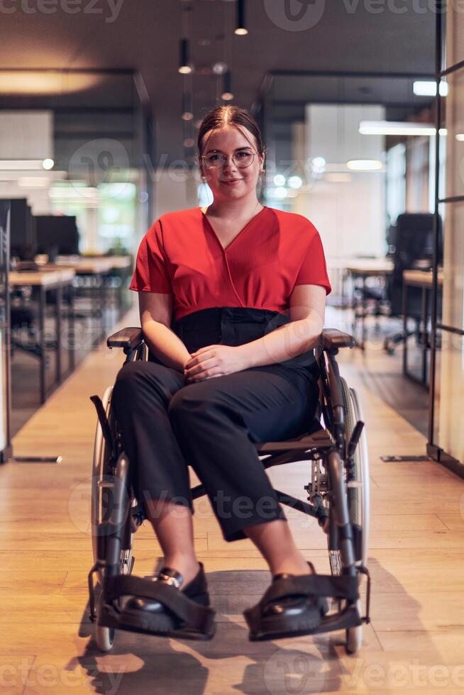 A modern young businesswoman in a wheelchair is surrounded by an inclusive workspace with glass-walled offices, embodying determination and innovation in the business world photo