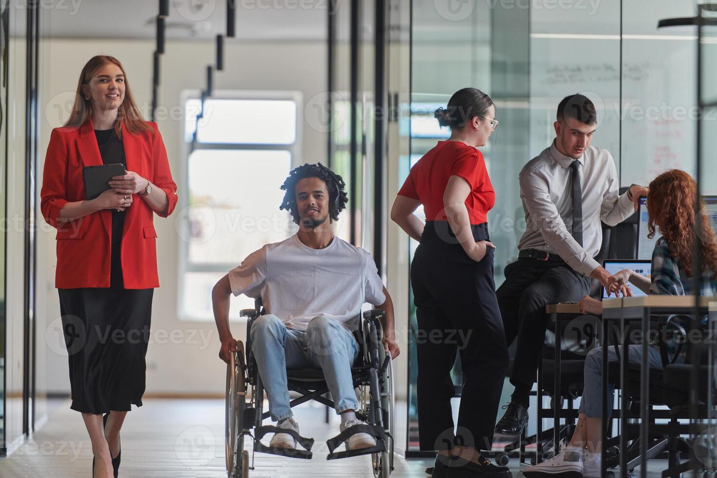 A group of young business people in a modern glass-walled office captures the essence of diversity and collaboration, while two colleagues, including an African American businessman in a wheelchair photo