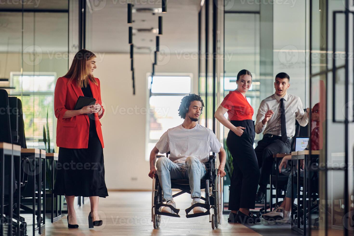 A group of young business people in a modern glass-walled office captures the essence of diversity and collaboration, while two colleagues, including an African American businessman in a wheelchair photo