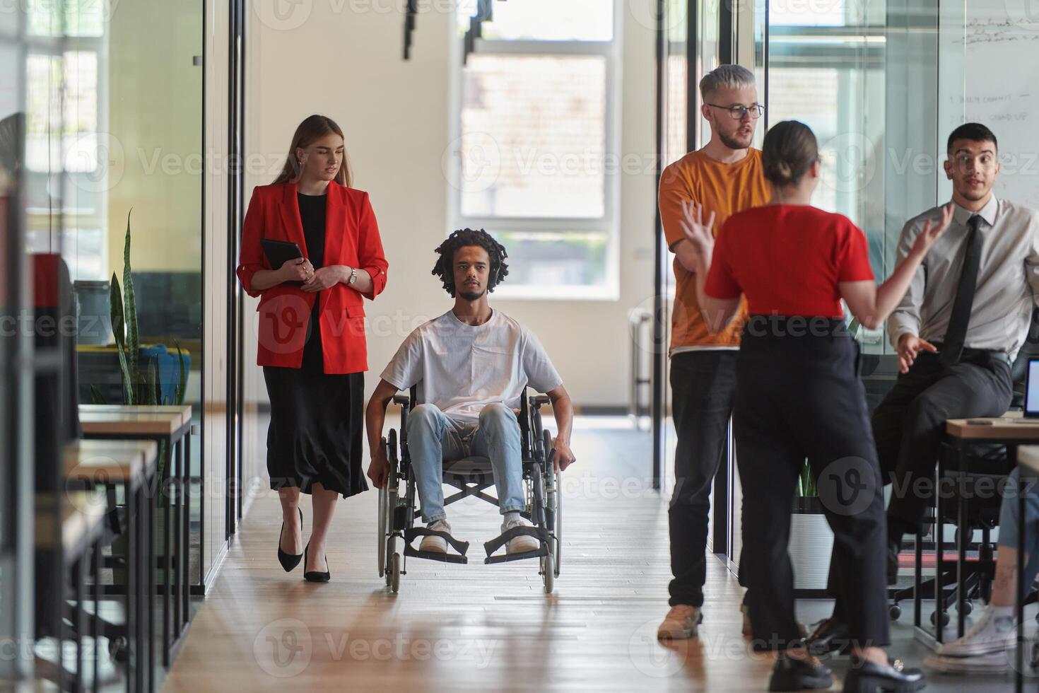 A group of young business people in a modern glass-walled office captures the essence of diversity and collaboration, while two colleagues, including an African American businessman in a wheelchair photo