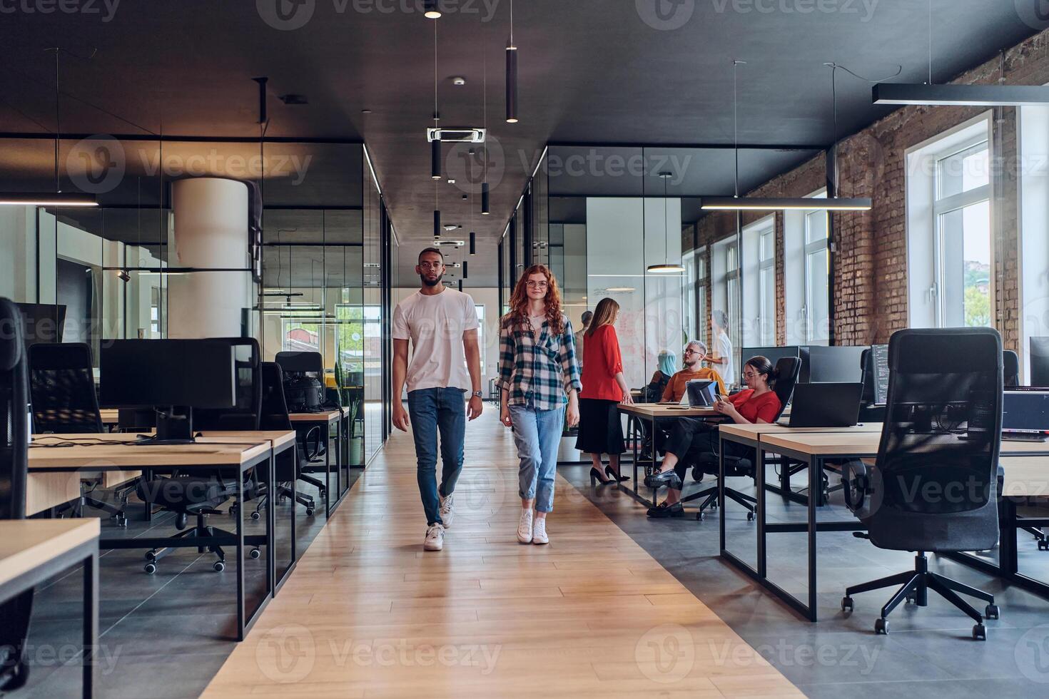 A young African American businessman and a modern businesswoman with orange hair stand side by side, arms crossed, exuding confidence and unity in a contemporary office setting, epitomizing dynamic photo