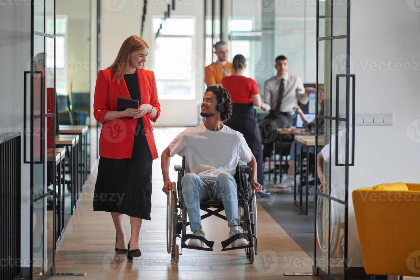 A group of young business people in a modern glass-walled office captures the essence of diversity and collaboration, while two colleagues, including an African American businessman in a wheelchair photo