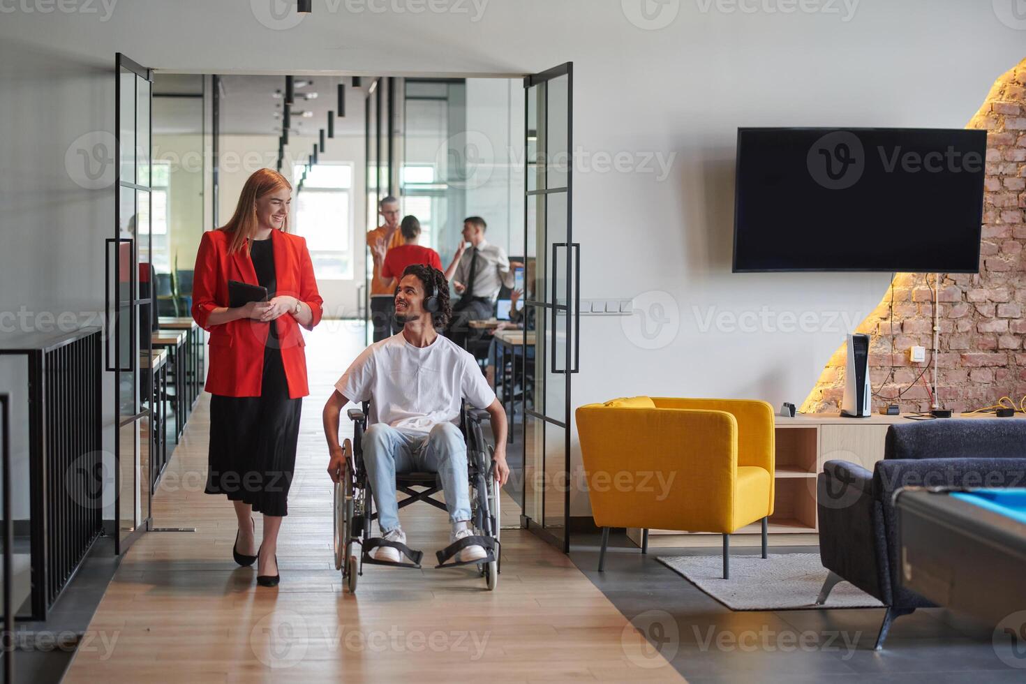 A group of young business people in a modern glass-walled office captures the essence of diversity and collaboration, while two colleagues, including an African American businessman in a wheelchair photo