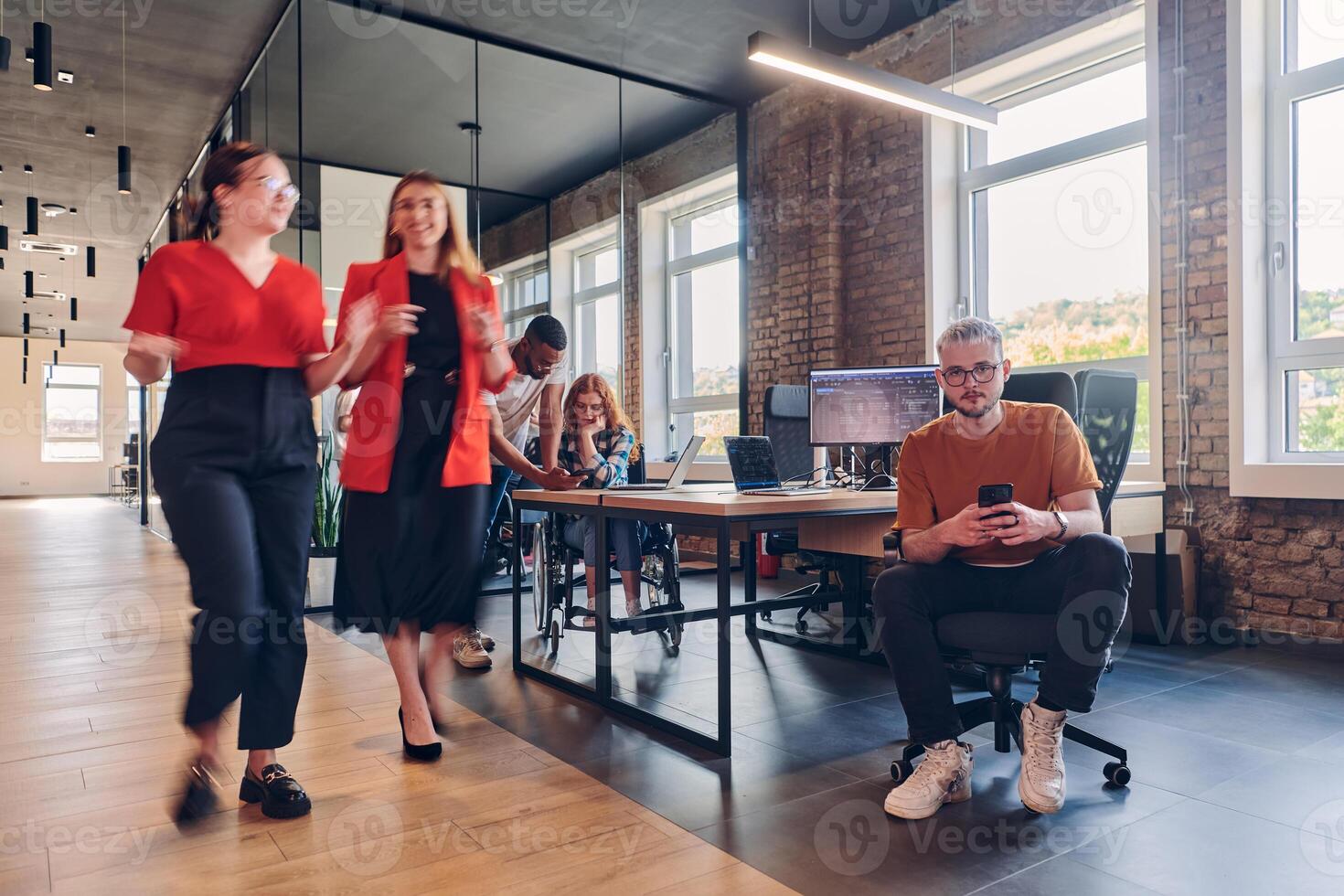 A diverse group of business professionals collaborates in a modern startup coworking center, utilizing a mix of paper-based and technological tools such as mobile phones and computers to collectively photo