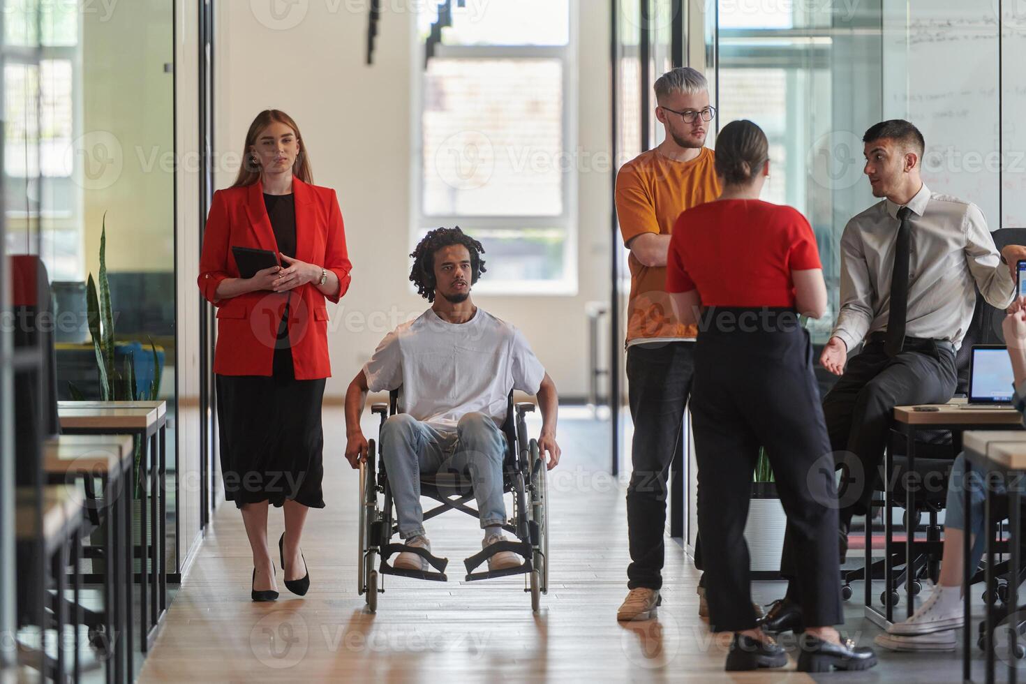 A group of young business people in a modern glass-walled office captures the essence of diversity and collaboration, while two colleagues, including an African American businessman in a wheelchair photo