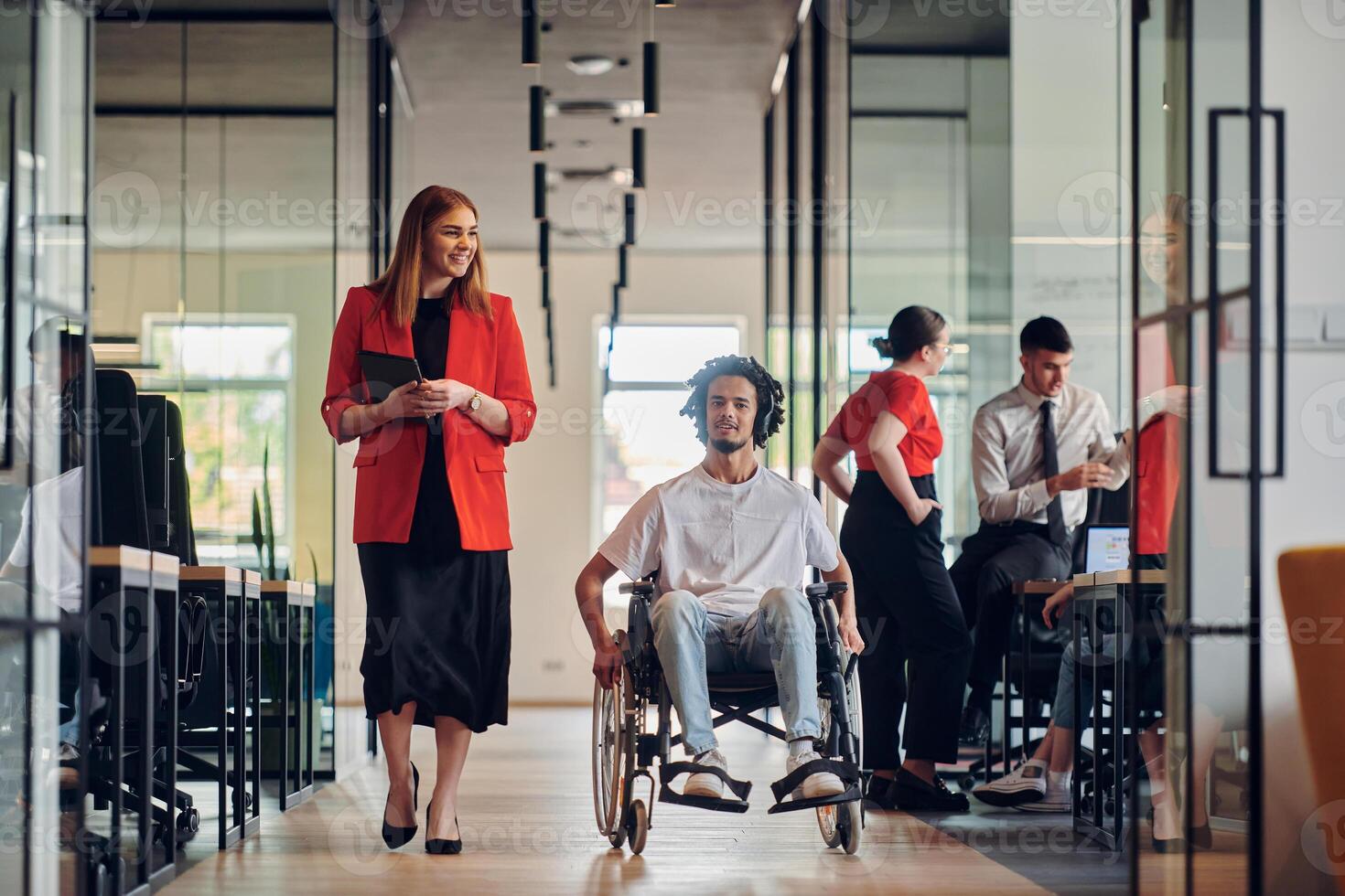A group of young business people in a modern glass-walled office captures the essence of diversity and collaboration, while two colleagues, including an African American businessman in a wheelchair photo