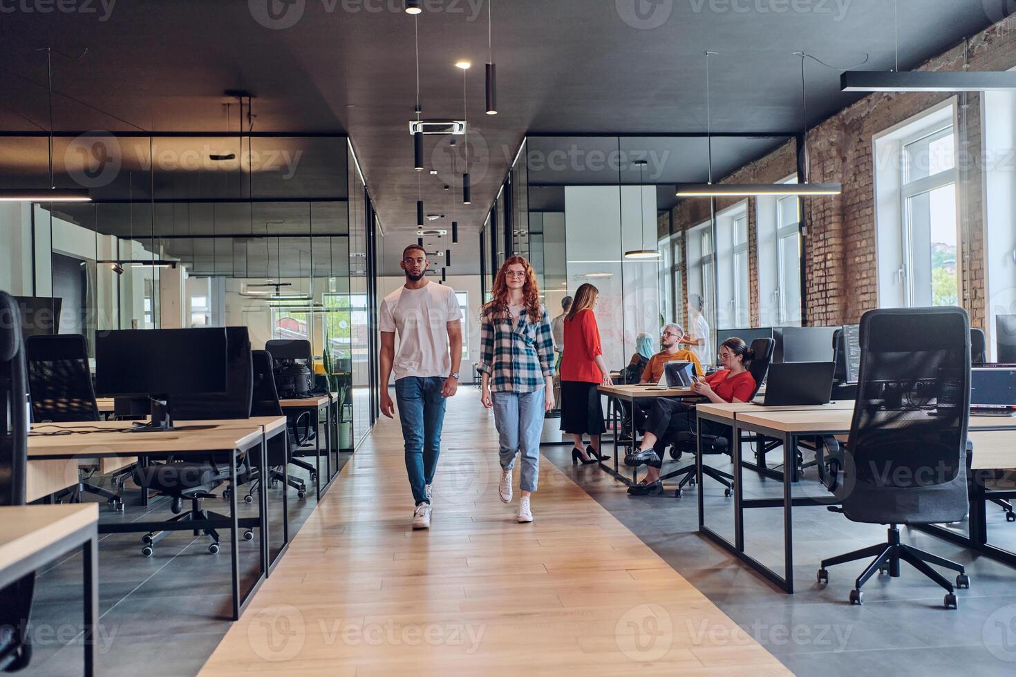 A young African American businessman and a modern businesswoman with orange hair stand side by side, arms crossed, exuding confidence and unity in a contemporary office setting, epitomizing dynamic photo