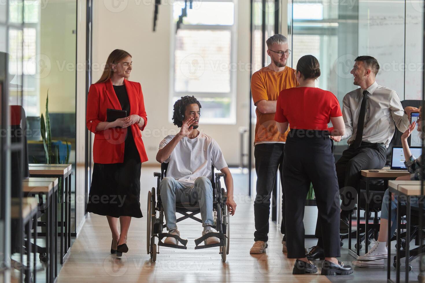 A group of young business people in a modern glass-walled office captures the essence of diversity and collaboration, while two colleagues, including an African American businessman in a wheelchair photo