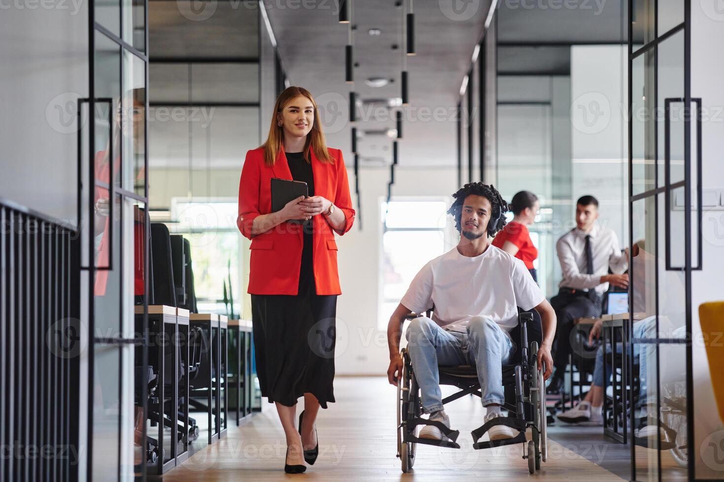 A group of young business people in a modern glass-walled office captures the essence of diversity and collaboration, while two colleagues, including an African American businessman in a wheelchair photo
