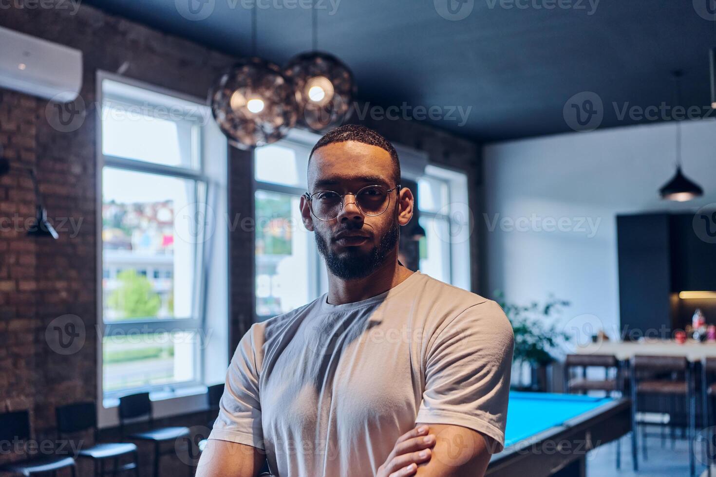 An African American businessman posing with crossed arms, exuding confidence and empowerment within the modern business setting of a startup coworking center. photo