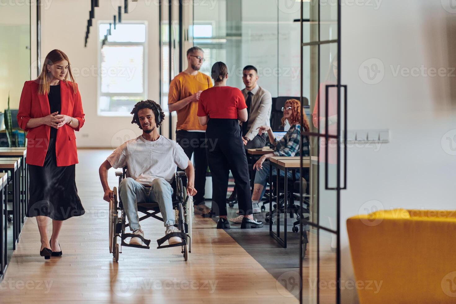 A group of young business people in a modern glass-walled office captures the essence of diversity and collaboration, while two colleagues, including an African American businessman in a wheelchair photo