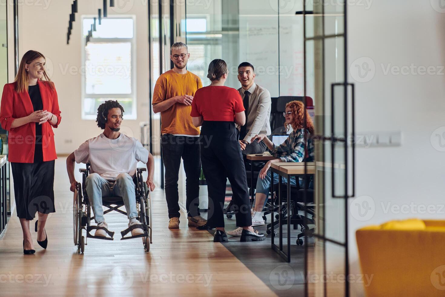 A group of young business people in a modern glass-walled office captures the essence of diversity and collaboration, while two colleagues, including an African American businessman in a wheelchair photo
