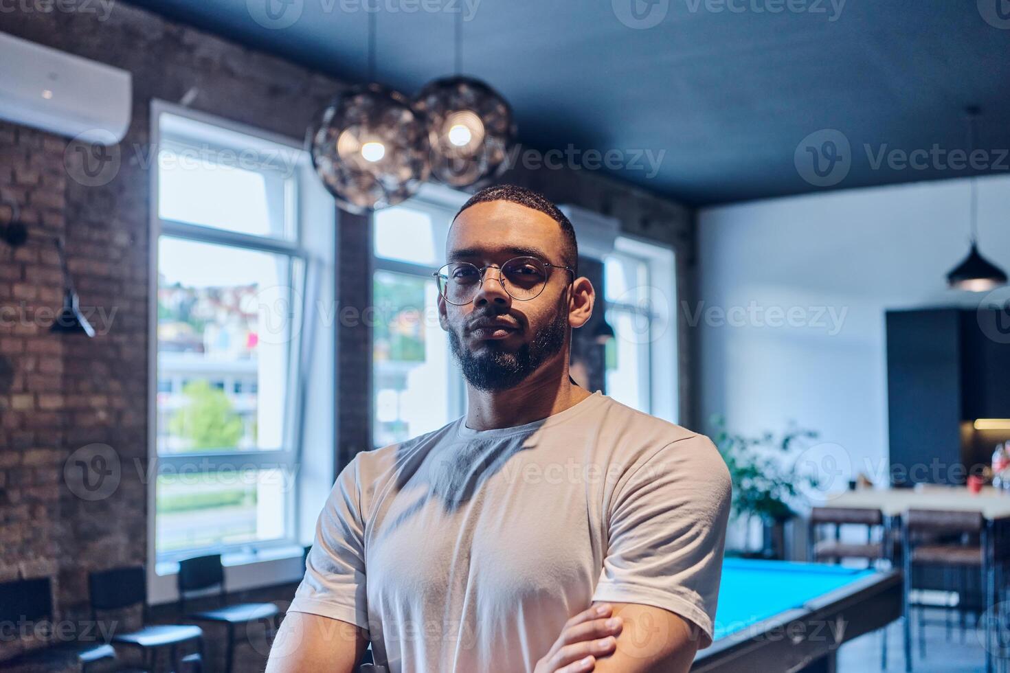 An African American businessman posing with crossed arms, exuding confidence and empowerment within the modern business setting of a startup coworking center. photo