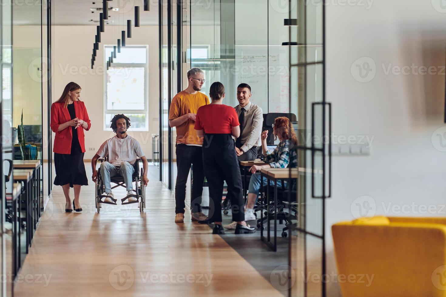 A group of young business people in a modern glass-walled office captures the essence of diversity and collaboration, while two colleagues, including an African American businessman in a wheelchair photo