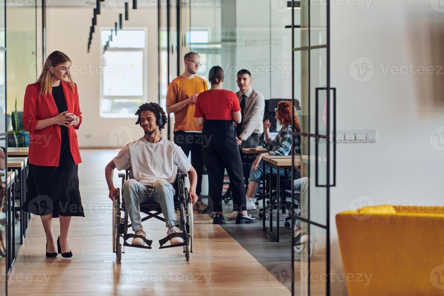 A group of young business people in a modern glass-walled office captures the essence of diversity and collaboration, while two colleagues, including an African American businessman in a wheelchair photo