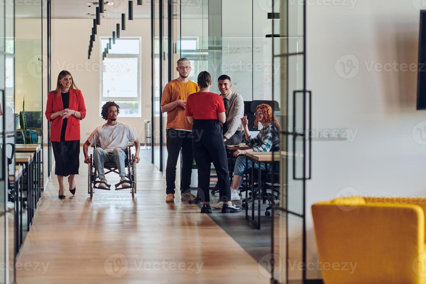 A group of young business people in a modern glass-walled office captures the essence of diversity and collaboration, while two colleagues, including an African American businessman in a wheelchair photo