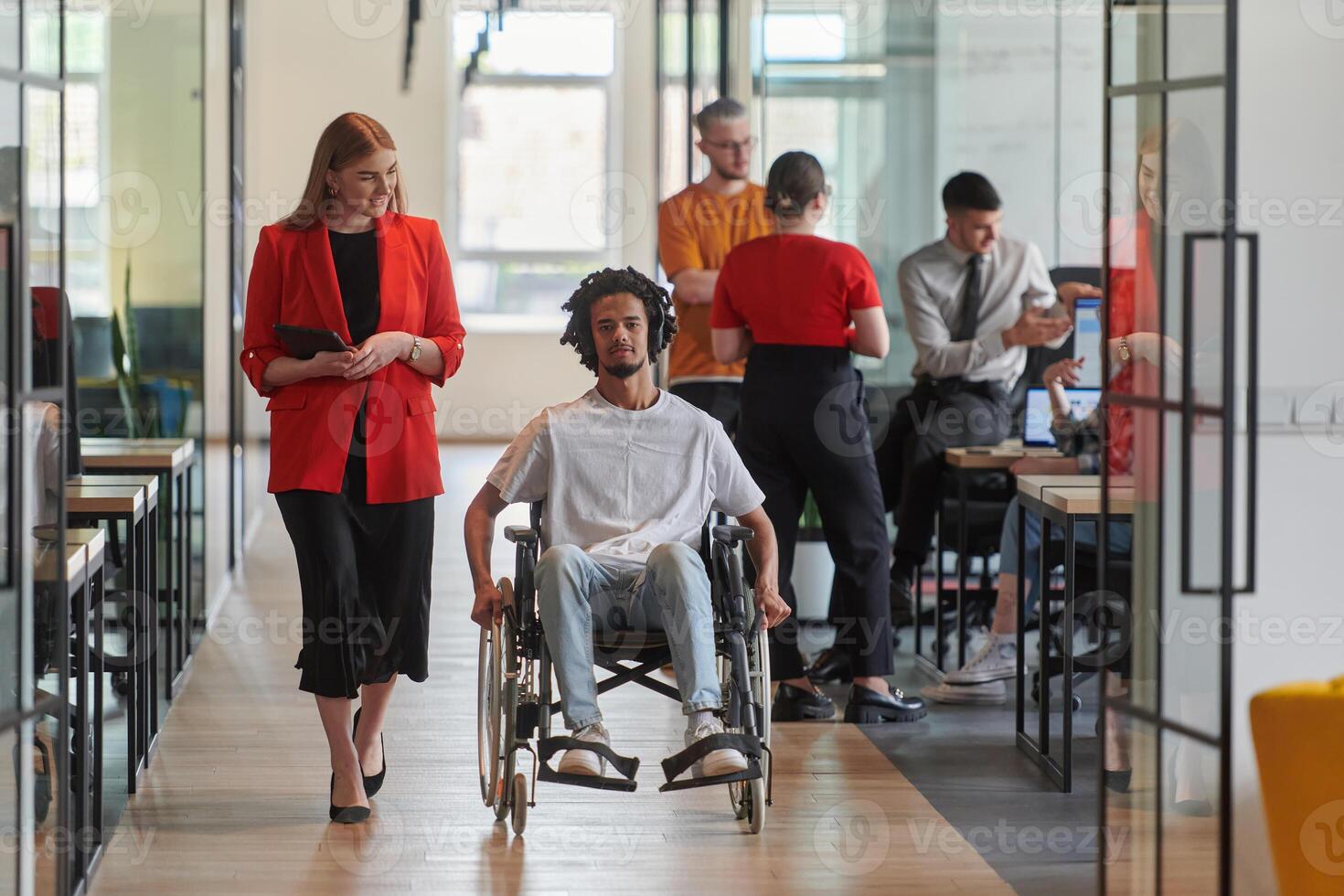 A group of young business people in a modern glass-walled office captures the essence of diversity and collaboration, while two colleagues, including an African American businessman in a wheelchair photo