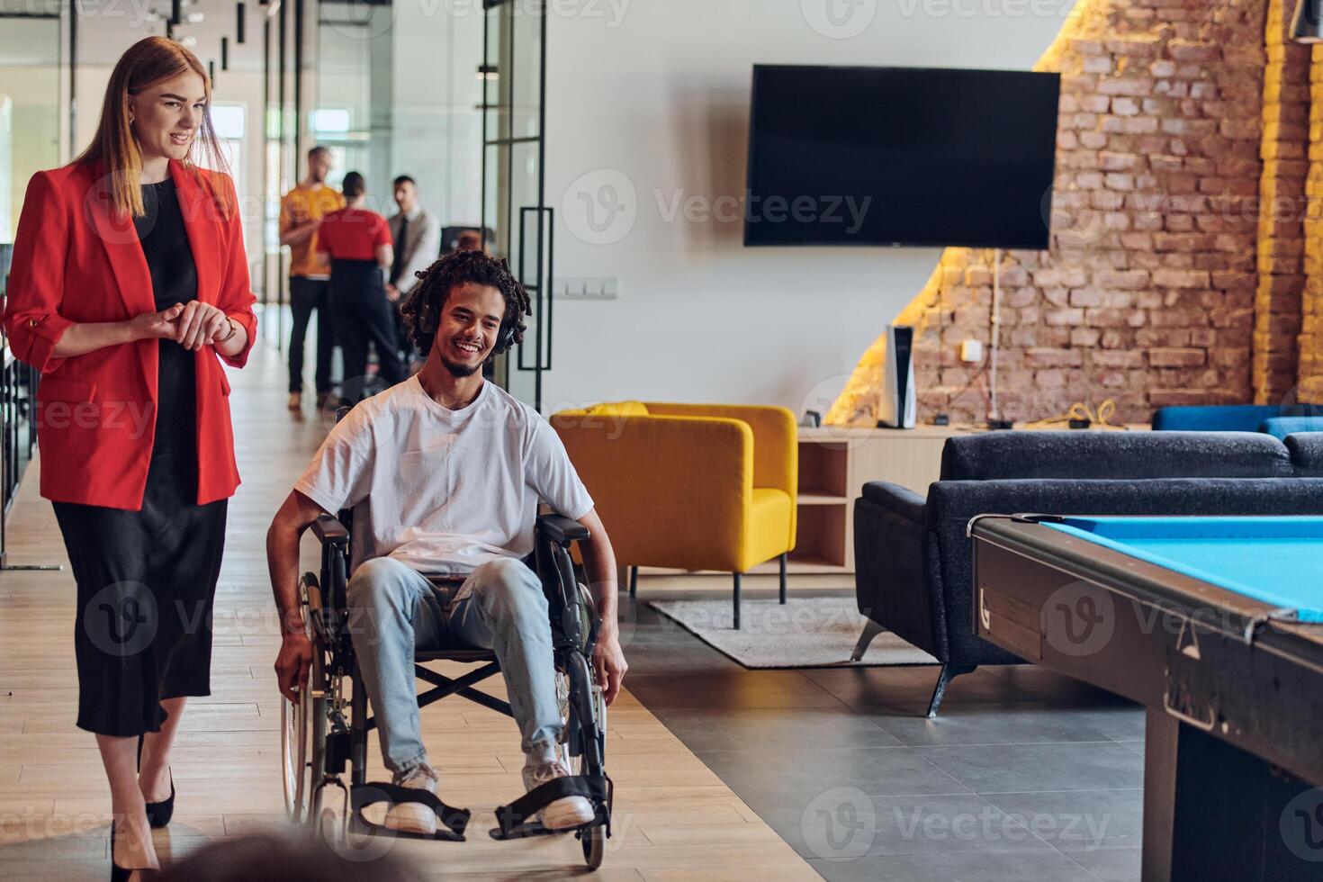 A group of young business people in a modern glass-walled office captures the essence of diversity and collaboration, while two colleagues, including an African American businessman in a wheelchair photo