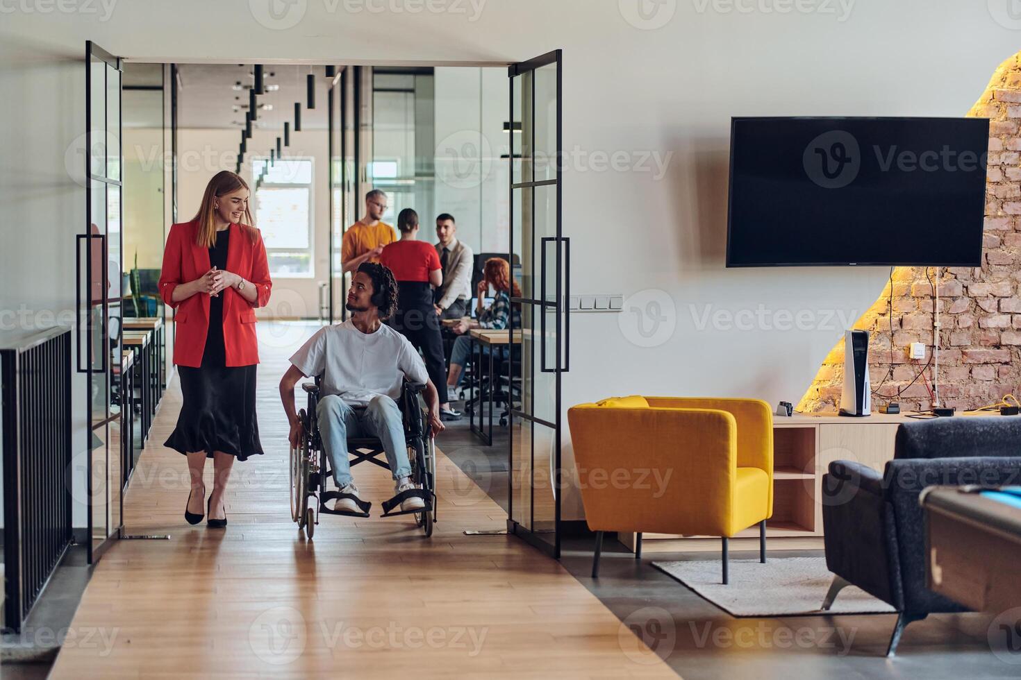 A group of young business people in a modern glass-walled office captures the essence of diversity and collaboration, while two colleagues, including an African American businessman in a wheelchair photo