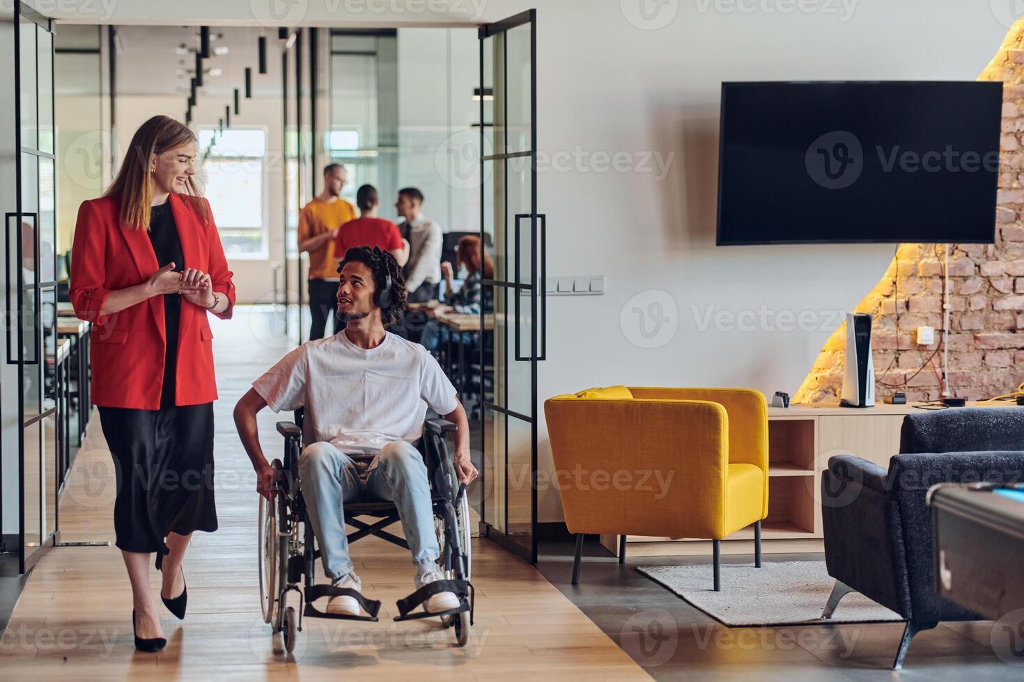 A group of young business people in a modern glass-walled office captures the essence of diversity and collaboration, while two colleagues, including an African American businessman in a wheelchair photo