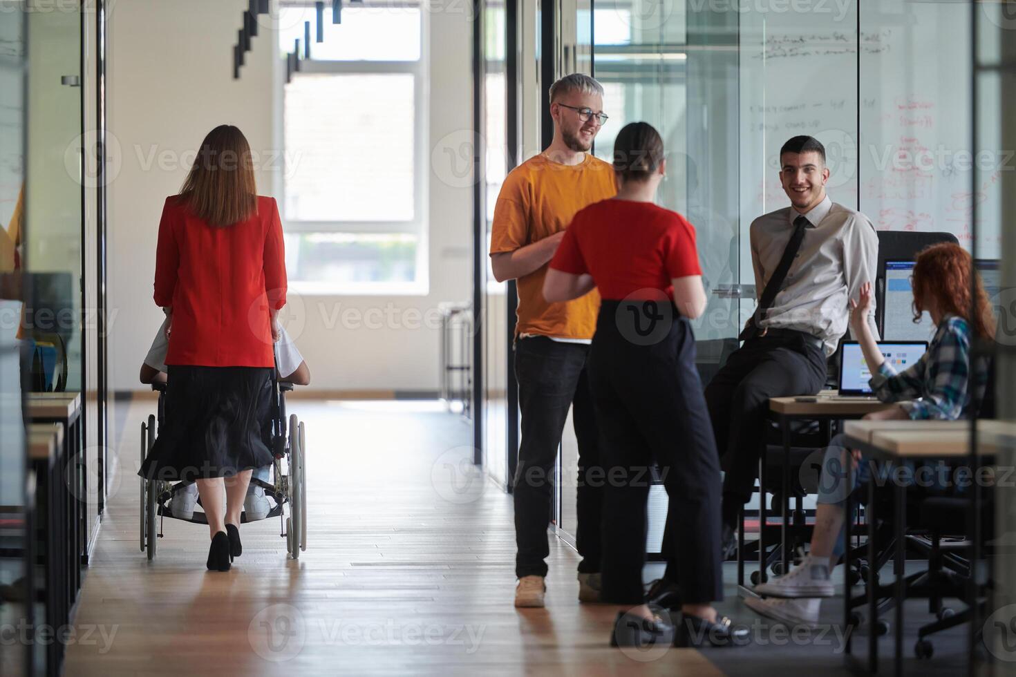 A group of young business people in a modern glass-walled office captures the essence of diversity and collaboration, while two colleagues, including an African American businessman in a wheelchair photo