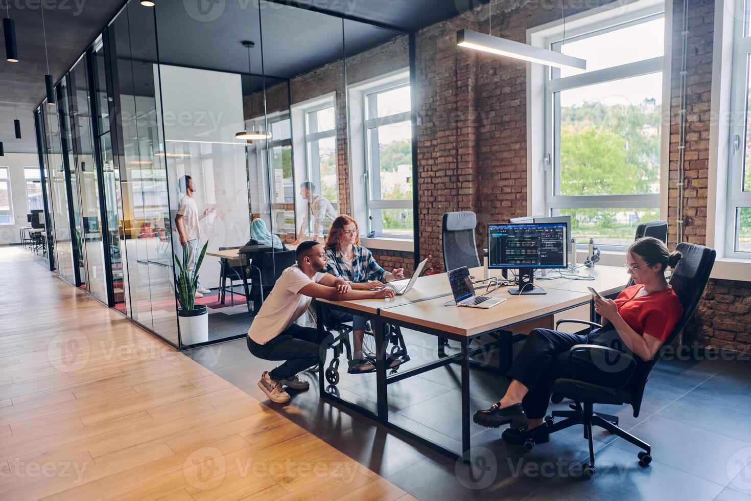 A diverse group of business professionals collaborates in a modern startup coworking center, utilizing a mix of paper-based and technological tools such as mobile phones and computers to collectively photo