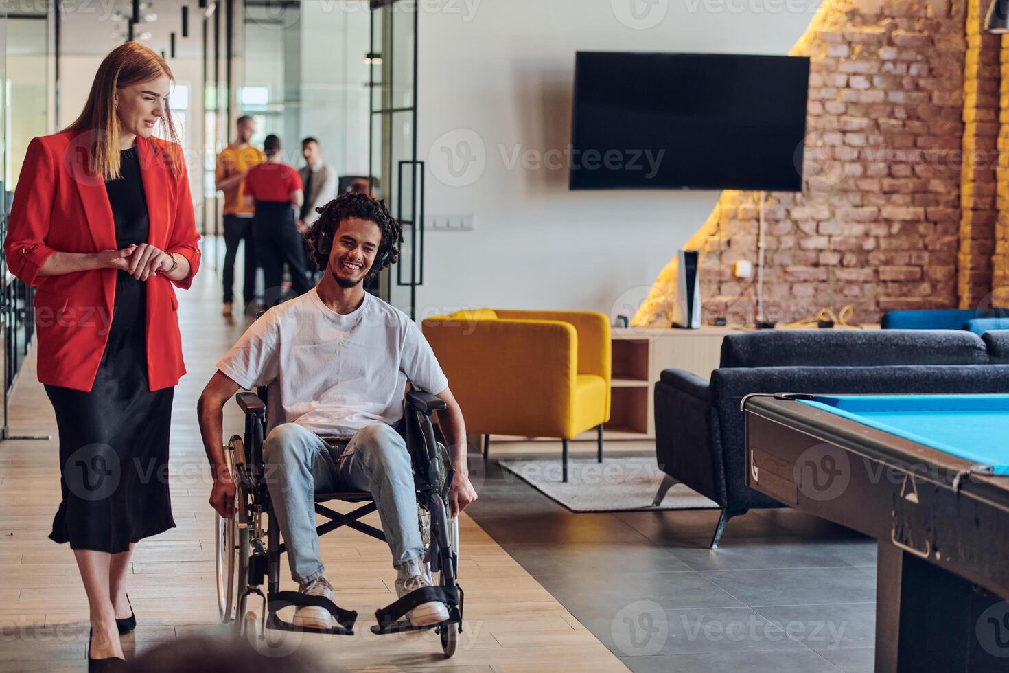 A group of young business people in a modern glass-walled office captures the essence of diversity and collaboration, while two colleagues, including an African American businessman in a wheelchair photo