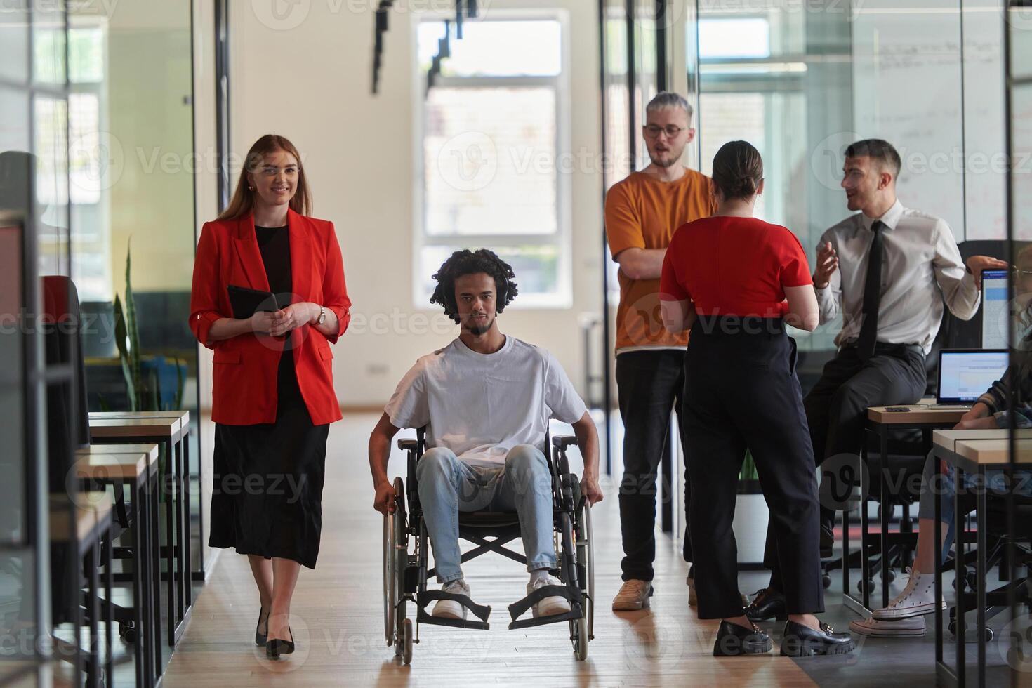 A group of young business people in a modern glass-walled office captures the essence of diversity and collaboration, while two colleagues, including an African American businessman in a wheelchair photo
