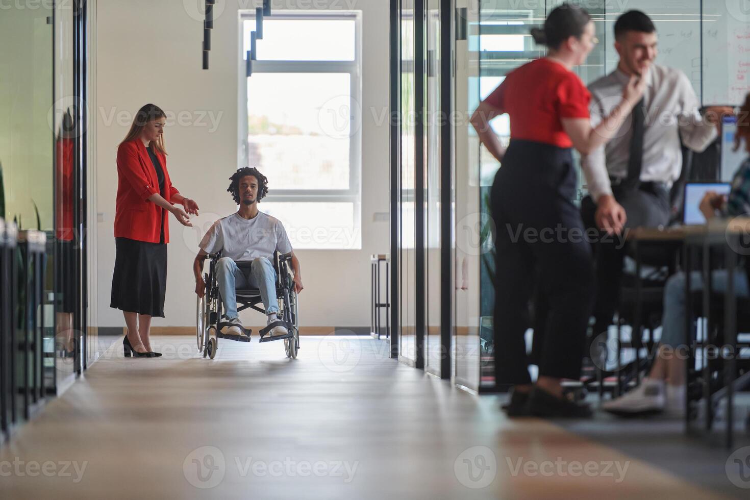 A group of young business people in a modern glass-walled office captures the essence of diversity and collaboration, while two colleagues, including an African American businessman in a wheelchair photo