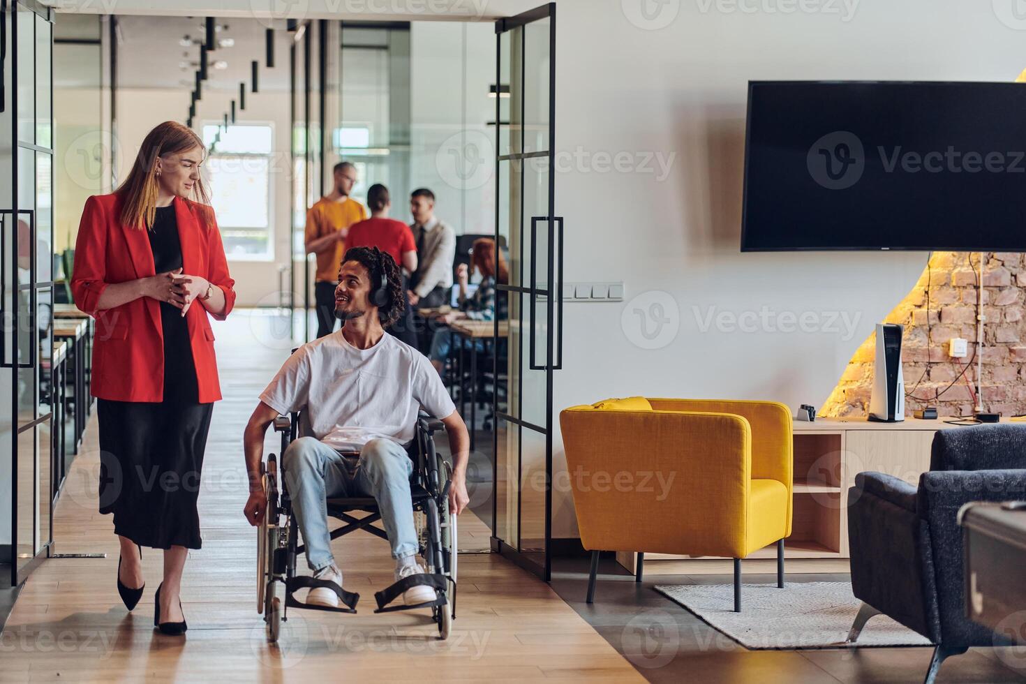 A group of young business people in a modern glass-walled office captures the essence of diversity and collaboration, while two colleagues, including an African American businessman in a wheelchair photo