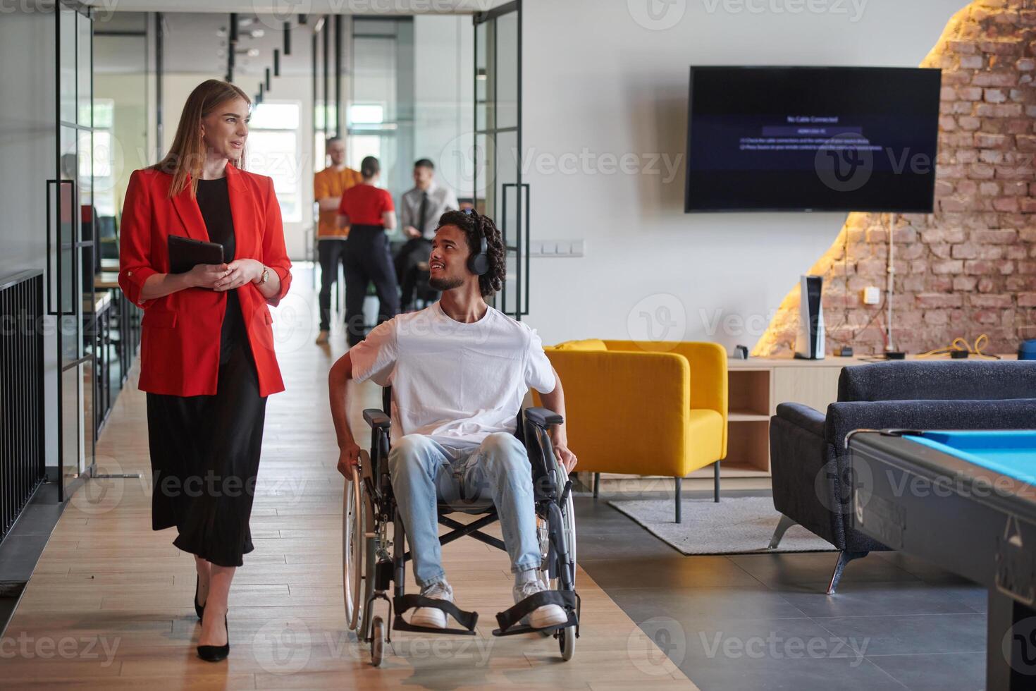 A group of young business people in a modern glass-walled office captures the essence of diversity and collaboration, while two colleagues, including an African American businessman in a wheelchair photo