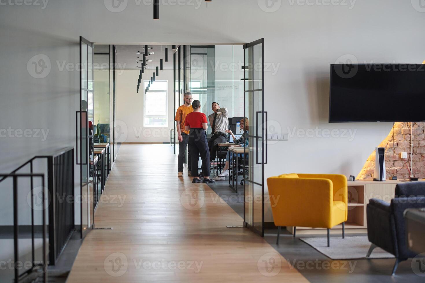A business group, including an African American businessman in a wheelchair, collaborates within a modern glass office, actively engaged around a computer and laptop, collectively solving diverse photo