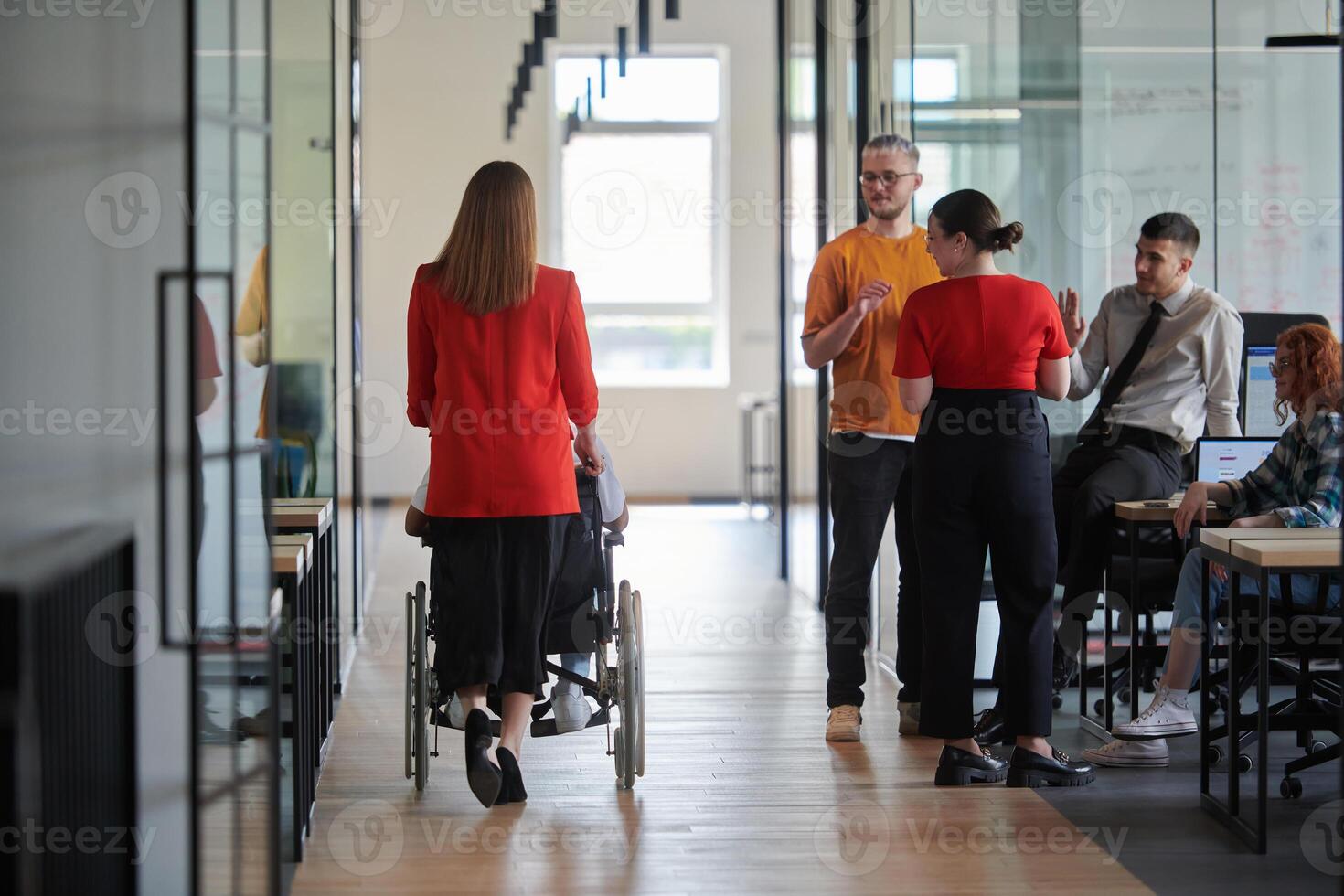 A group of young business people in a modern glass-walled office captures the essence of diversity and collaboration, while two colleagues, including an African American businessman in a wheelchair photo