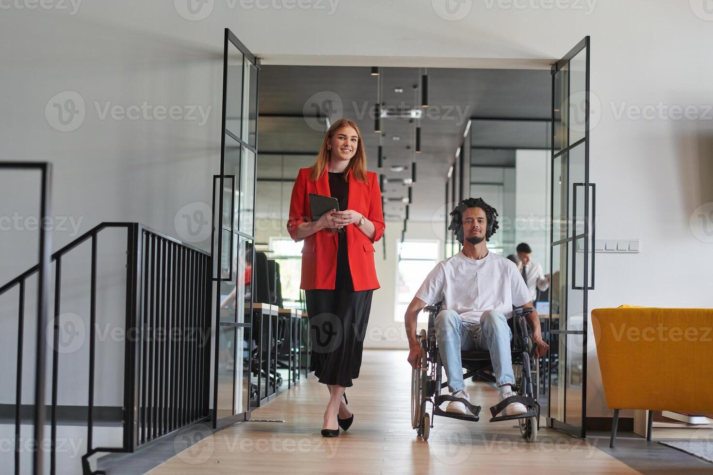 A group of young business people in a modern glass-walled office captures the essence of diversity and collaboration, while two colleagues, including an African American businessman in a wheelchair photo