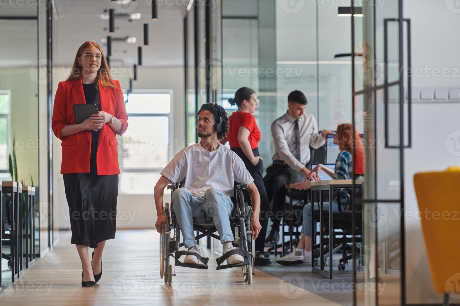 A group of young business people in a modern glass-walled office captures the essence of diversity and collaboration, while two colleagues, including an African American businessman in a wheelchair photo