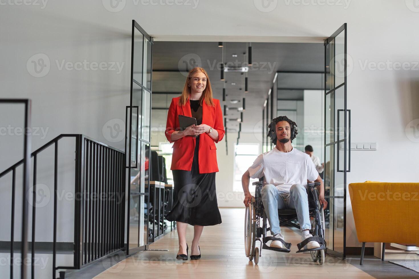 A group of young business people in a modern glass-walled office captures the essence of diversity and collaboration, while two colleagues, including an African American businessman in a wheelchair photo