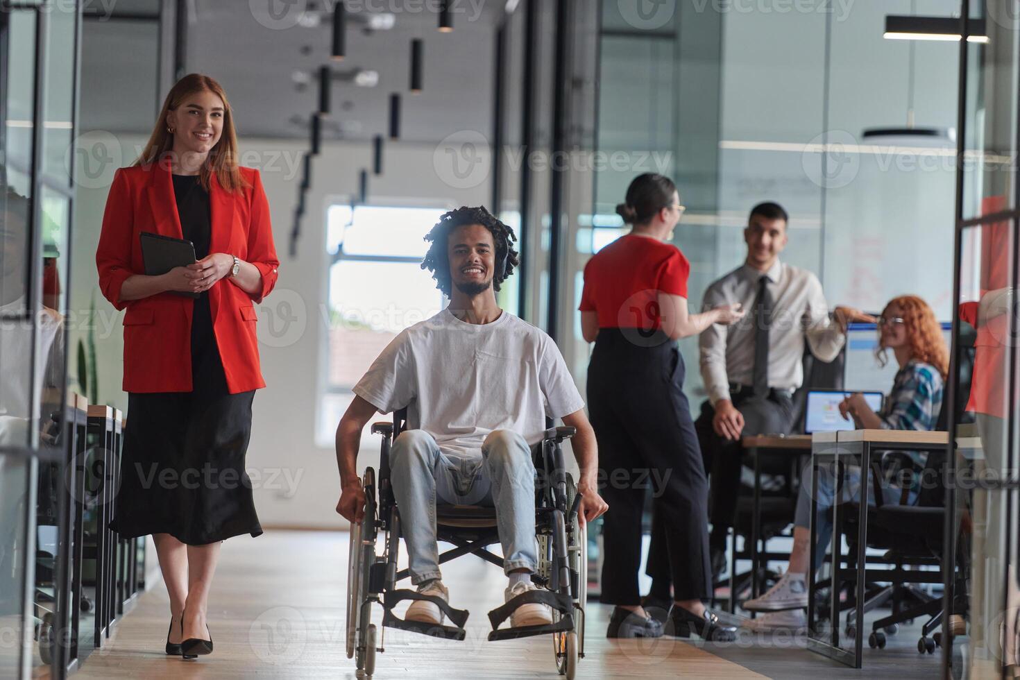 A group of young business people in a modern glass-walled office captures the essence of diversity and collaboration, while two colleagues, including an African American businessman in a wheelchair photo