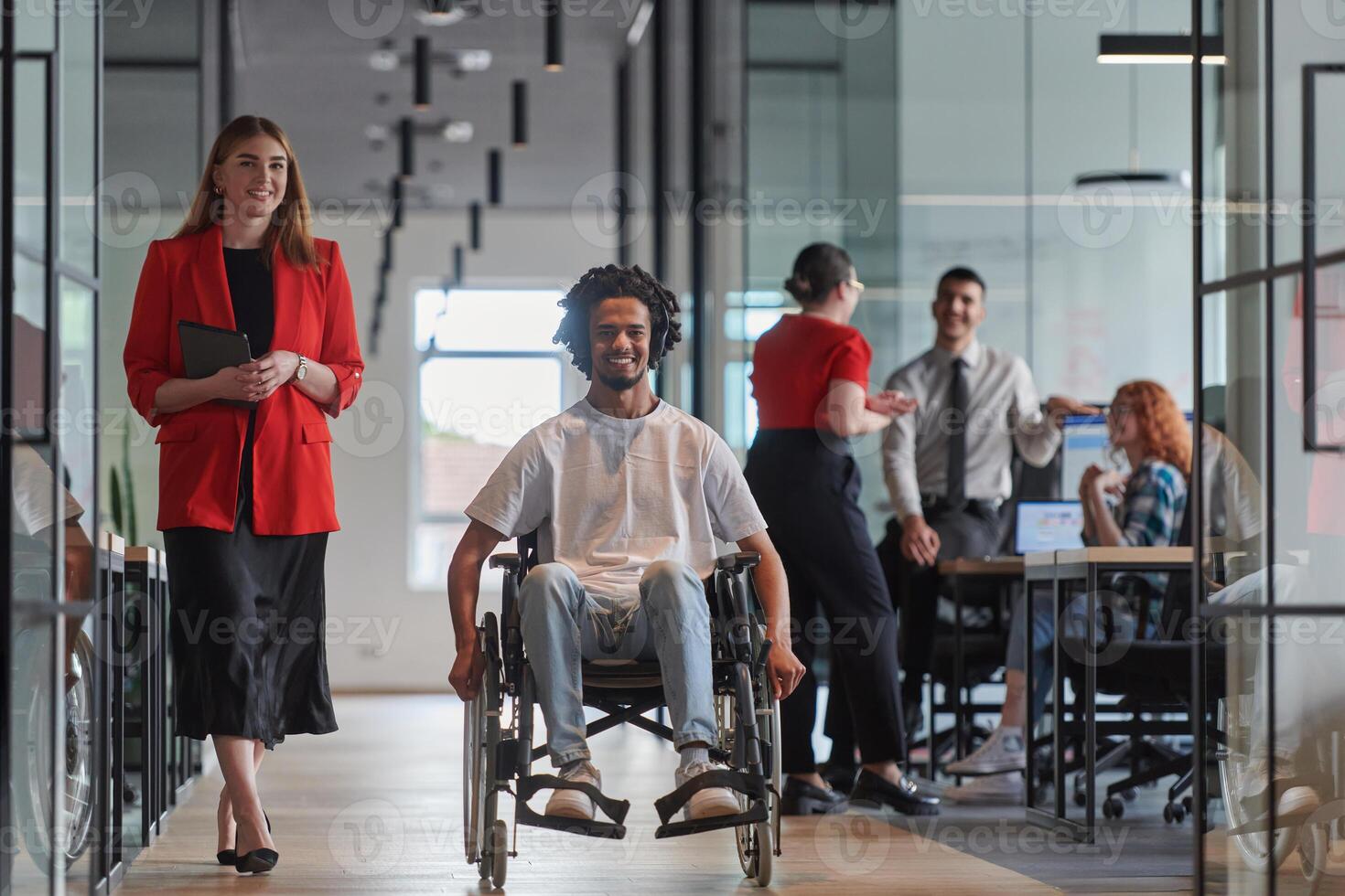 A group of young business people in a modern glass-walled office captures the essence of diversity and collaboration, while two colleagues, including an African American businessman in a wheelchair photo
