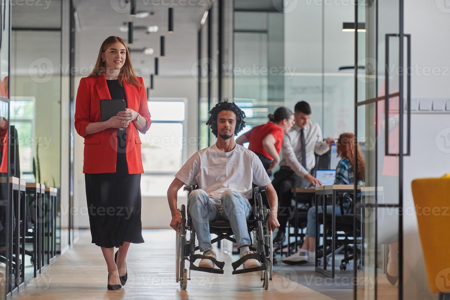 A group of young business people in a modern glass-walled office captures the essence of diversity and collaboration, while two colleagues, including an African American businessman in a wheelchair photo