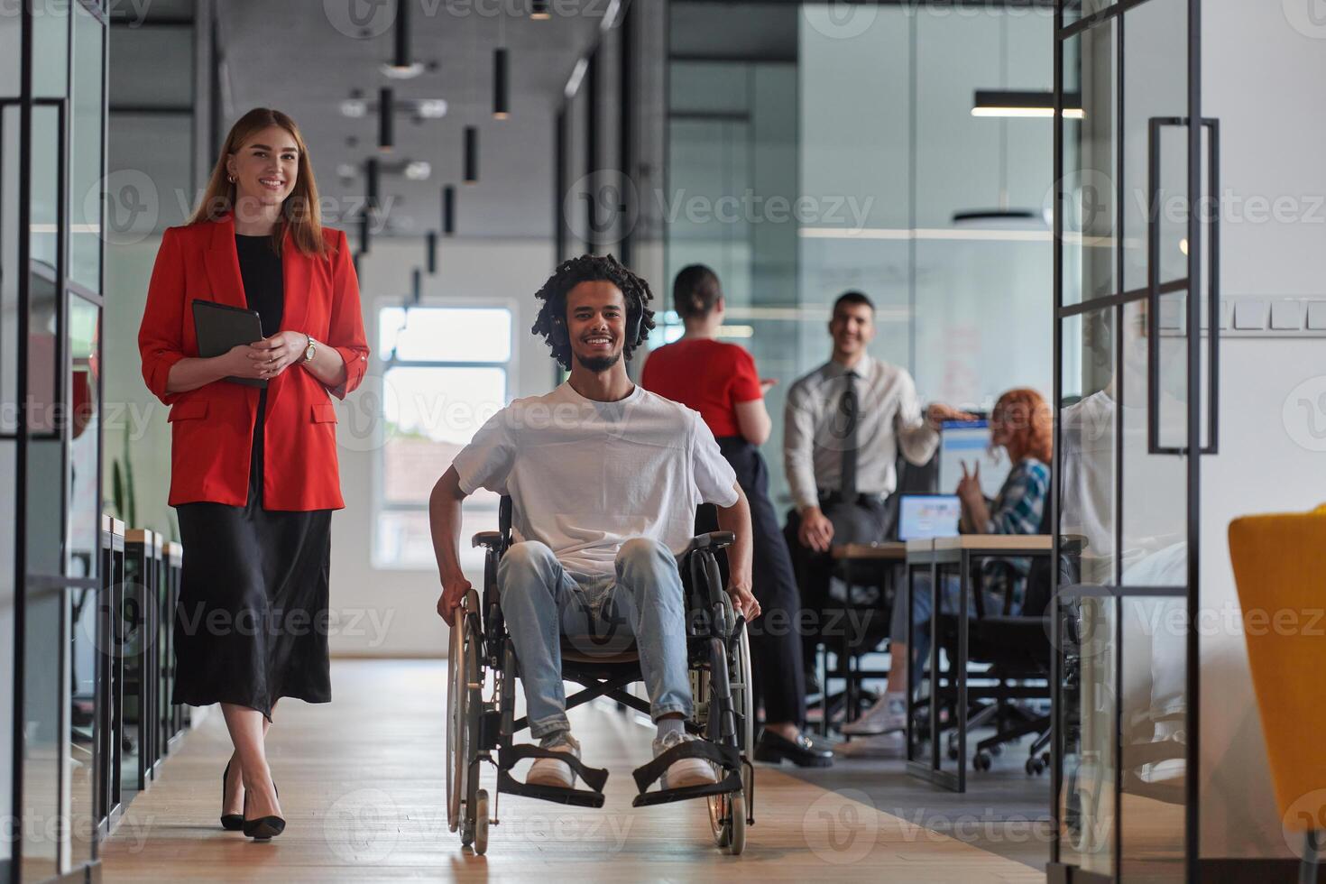 A group of young business people in a modern glass-walled office captures the essence of diversity and collaboration, while two colleagues, including an African American businessman in a wheelchair photo