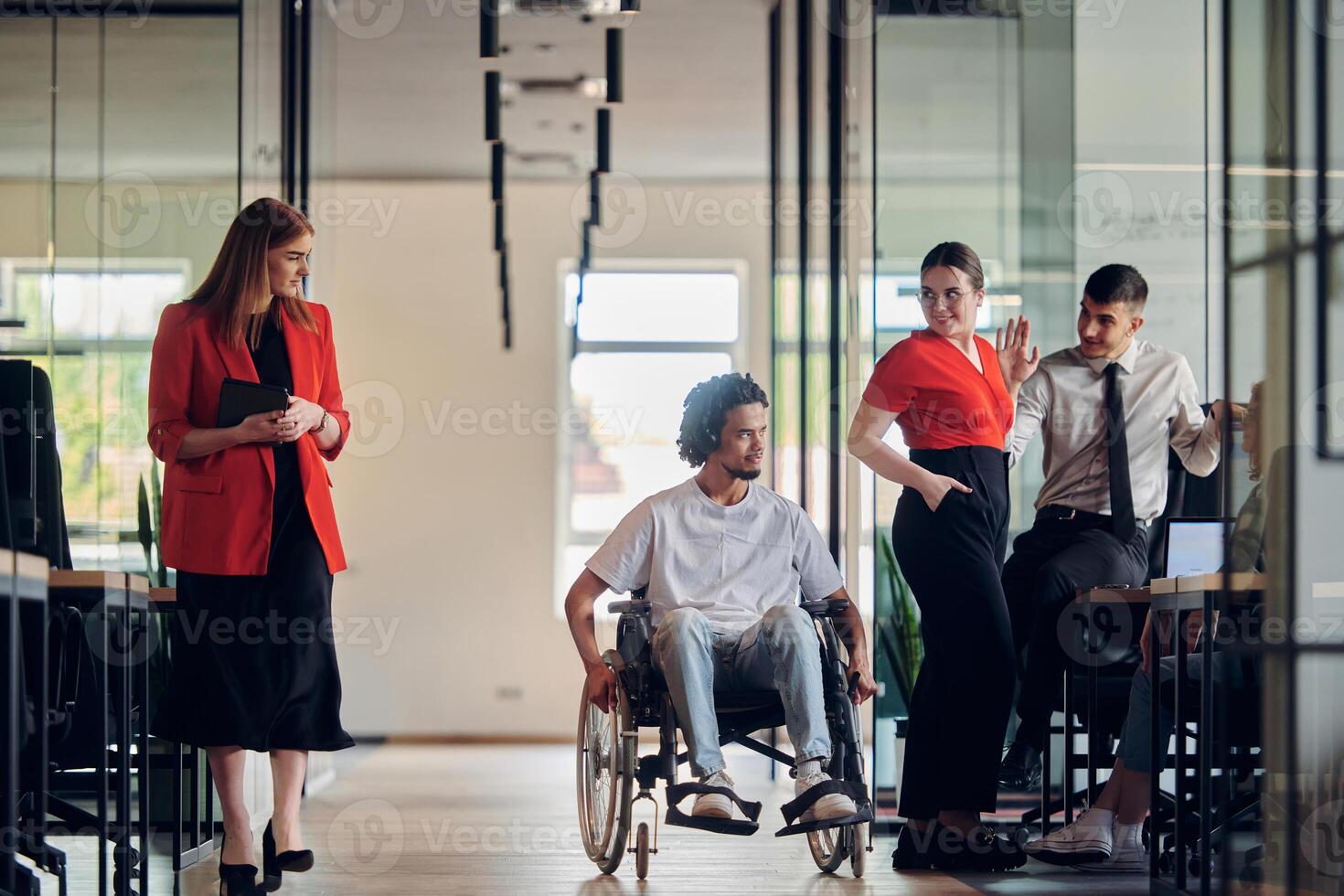 A group of young business people in a modern glass-walled office captures the essence of diversity and collaboration, while two colleagues, including an African American businessman in a wheelchair photo