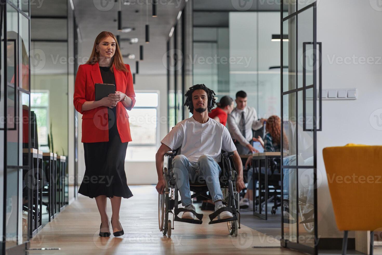 A group of young business people in a modern glass-walled office captures the essence of diversity and collaboration, while two colleagues, including an African American businessman in a wheelchair photo